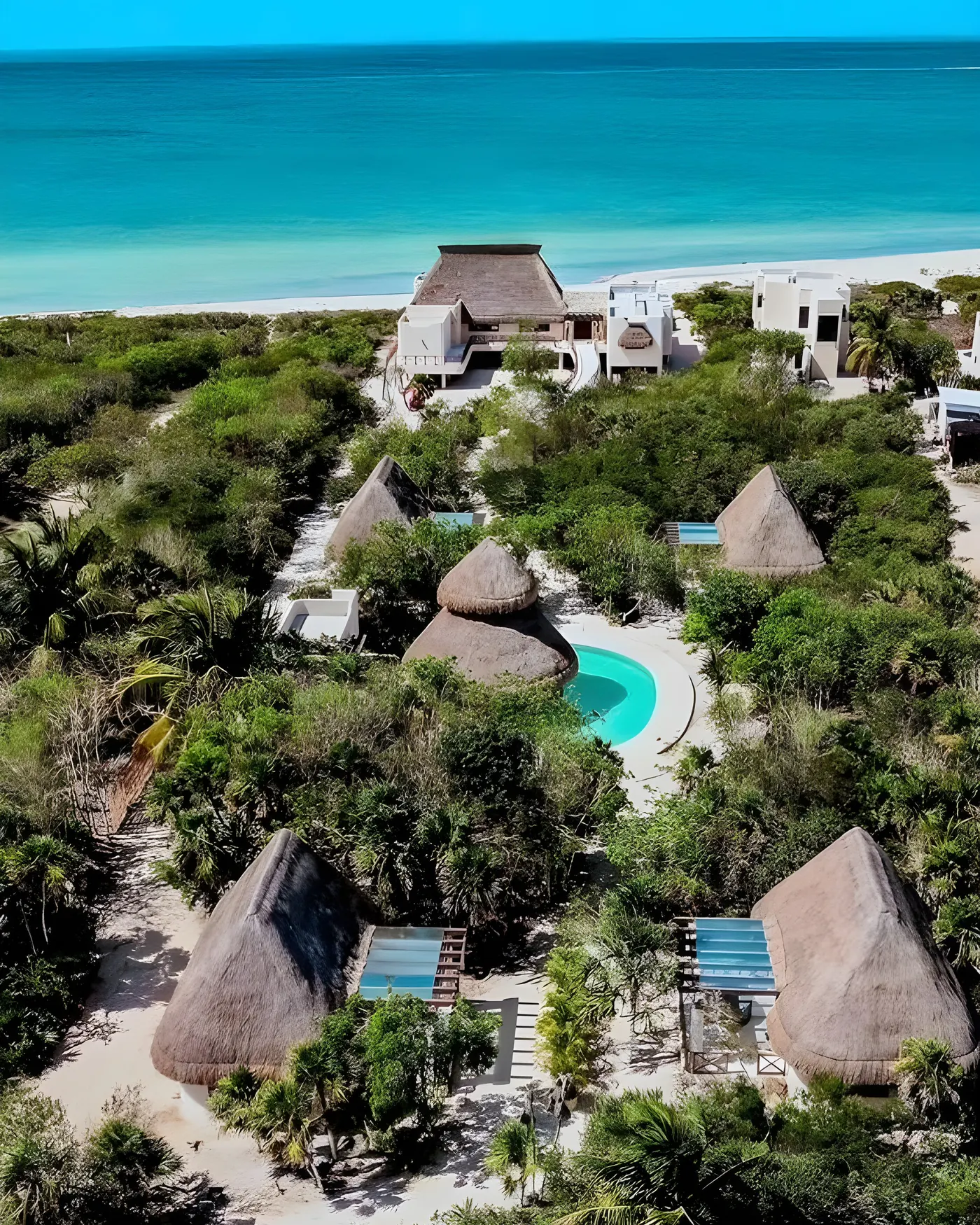 Vista aérea de toda la propiedad: bungalows de palapa, alberca y la playa de Sisal al fondo